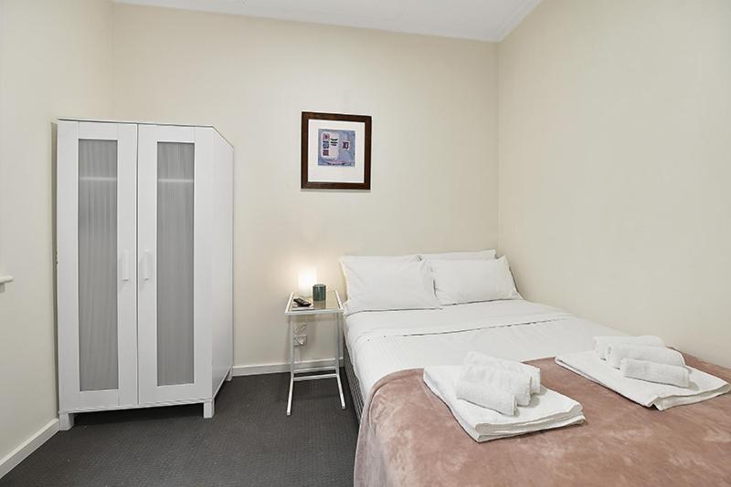 - une chambre blanche avec un lit et un bureau dans l'établissement Lovely One Bedroom Apt Next to RMIT! AC, 50inc TV, à Melbourne