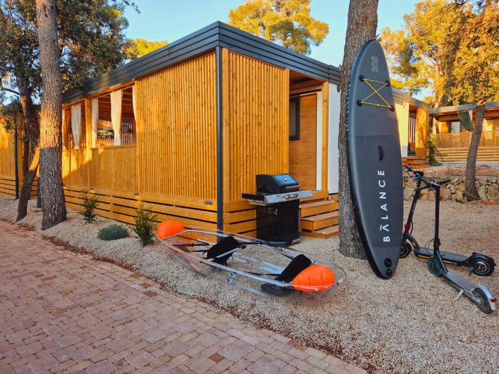 a kayak and a surfboard next to a cabin at Mobile home TASHA in Biograd na Moru