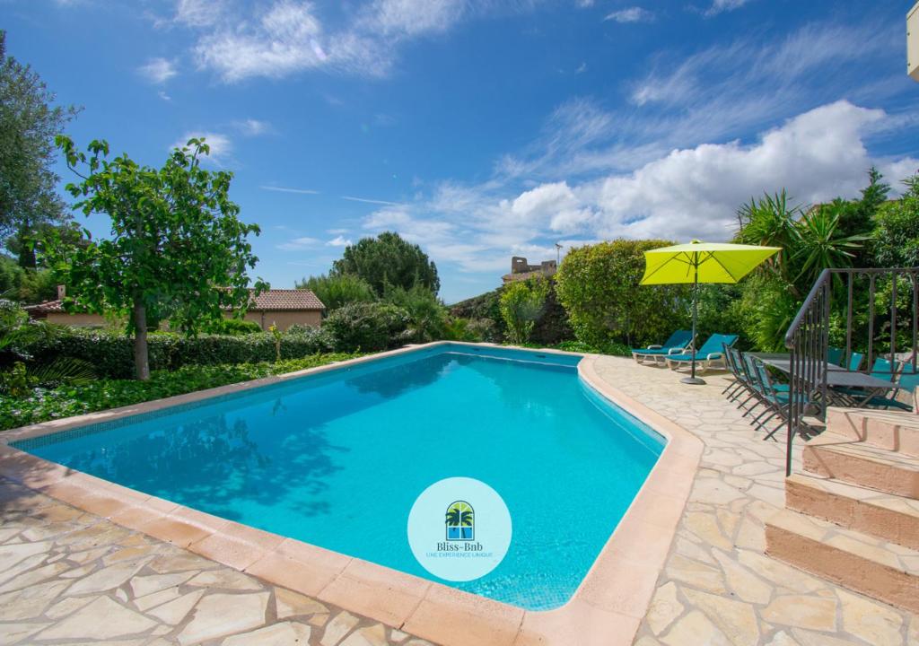 une piscine avec un parasol et deux chaises dans l'établissement Villa Ma Rosa, 160m2, 4ch, Piscine et Jardin, à Mandelieu-la-Napoule