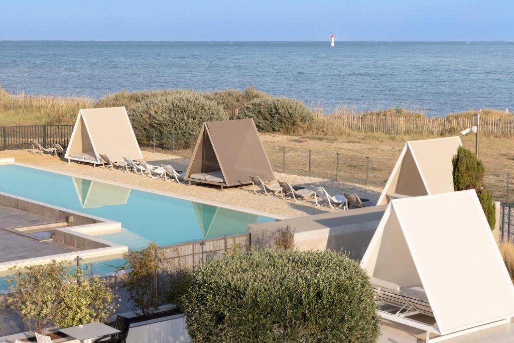 uma piscina com cadeiras e o oceano ao fundo em Atalante Relais Thalasso & Spa - Wellness Hôtel em Sainte-Marie-de-Ré