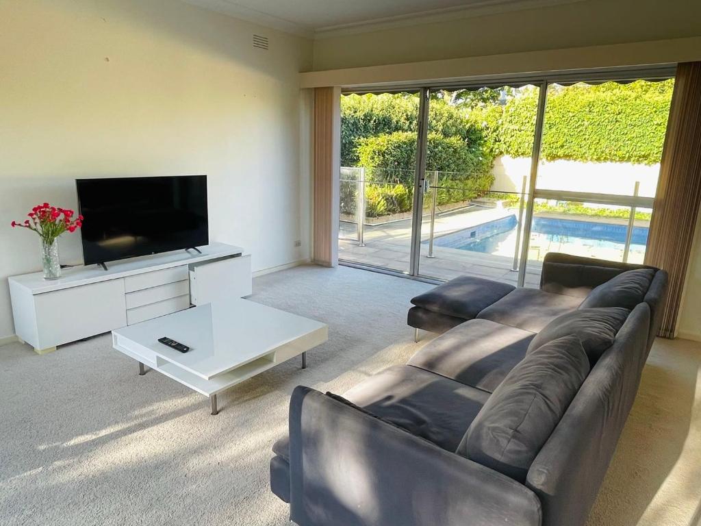 uma sala de estar com um sofá e uma televisão de ecrã plano em Home in Brighton em Melbourne