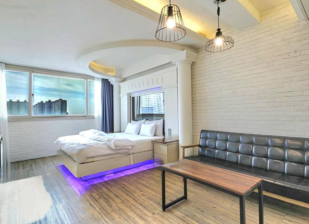a bedroom with a bed and a couch and a table at Hwamyeong Sky Hotel in Busan