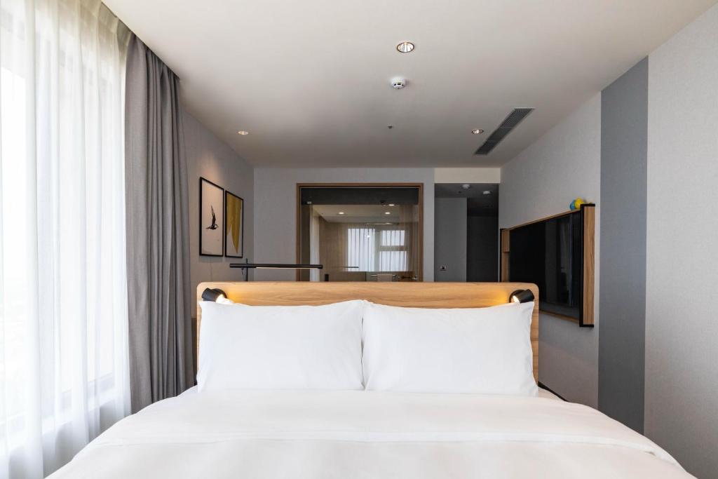 een slaapkamer met een wit bed met witte kussens bij voco Chiayi, an IHG Hotel in Chiayi City