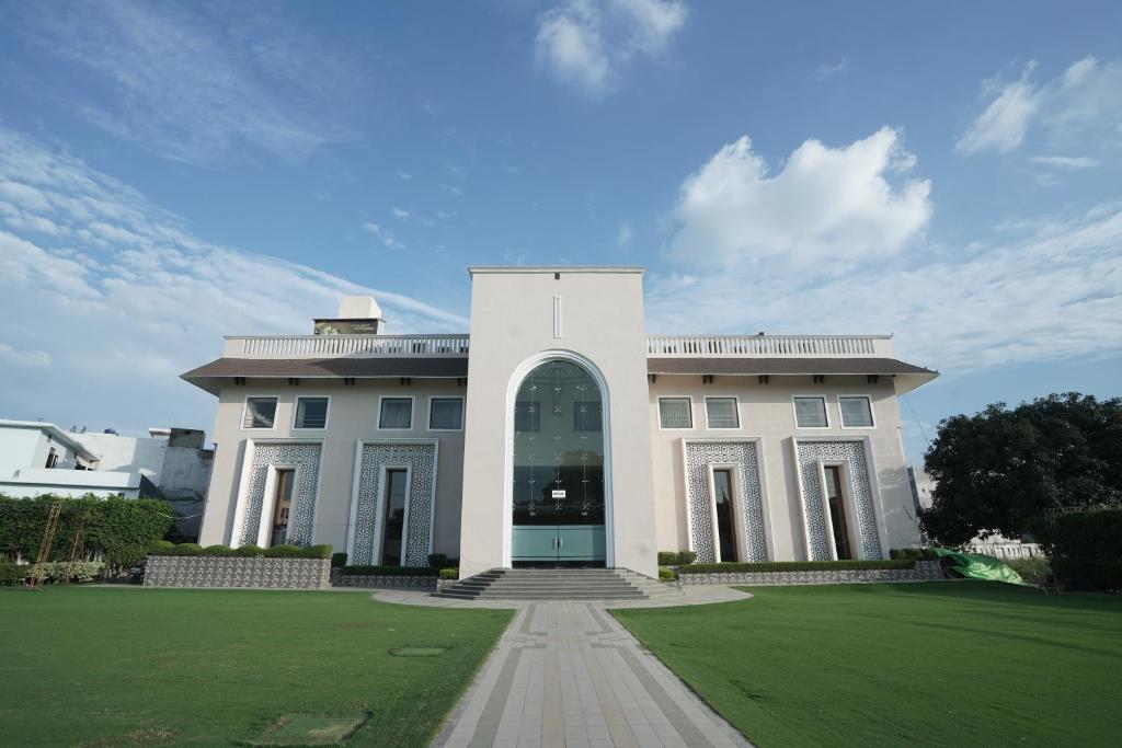 um grande edifício branco com um arco num campo em Nirmal Hotel And Resort em Bareilly