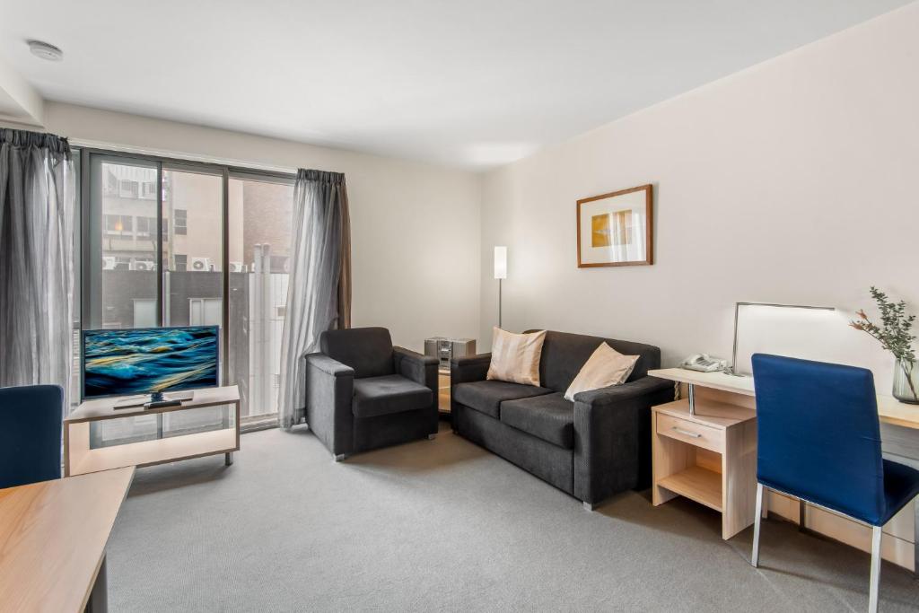 a living room with a couch and a tv at Central Melbourne CBD Apartment by Crown Casino in Melbourne
