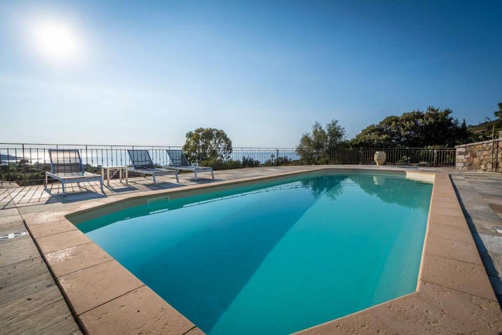 une piscine avec des chaises et l'océan en arrière-plan dans l'établissement Appartement 4 personnes - vue mer, à LʼÎle-Rousse