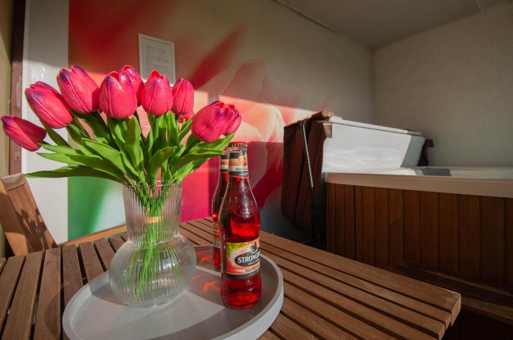 un vase de fleurs roses et une bouteille sur une table dans l'établissement Lilien Deluxe, à Gyula