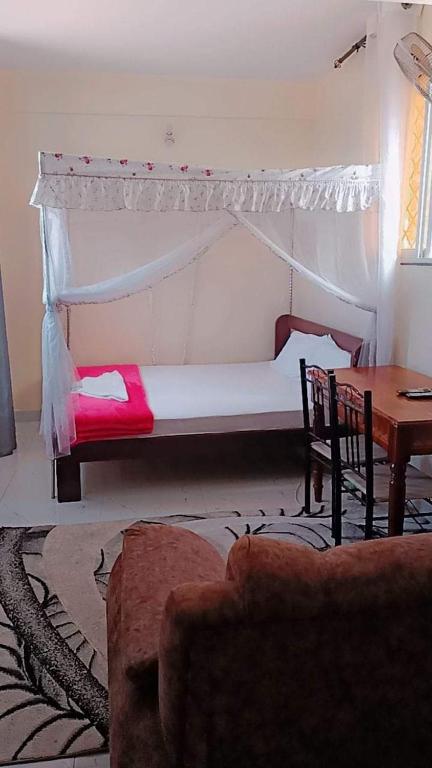 a bedroom with a bed with a canopy and a table at Mombasa comfy studio in Mombasa