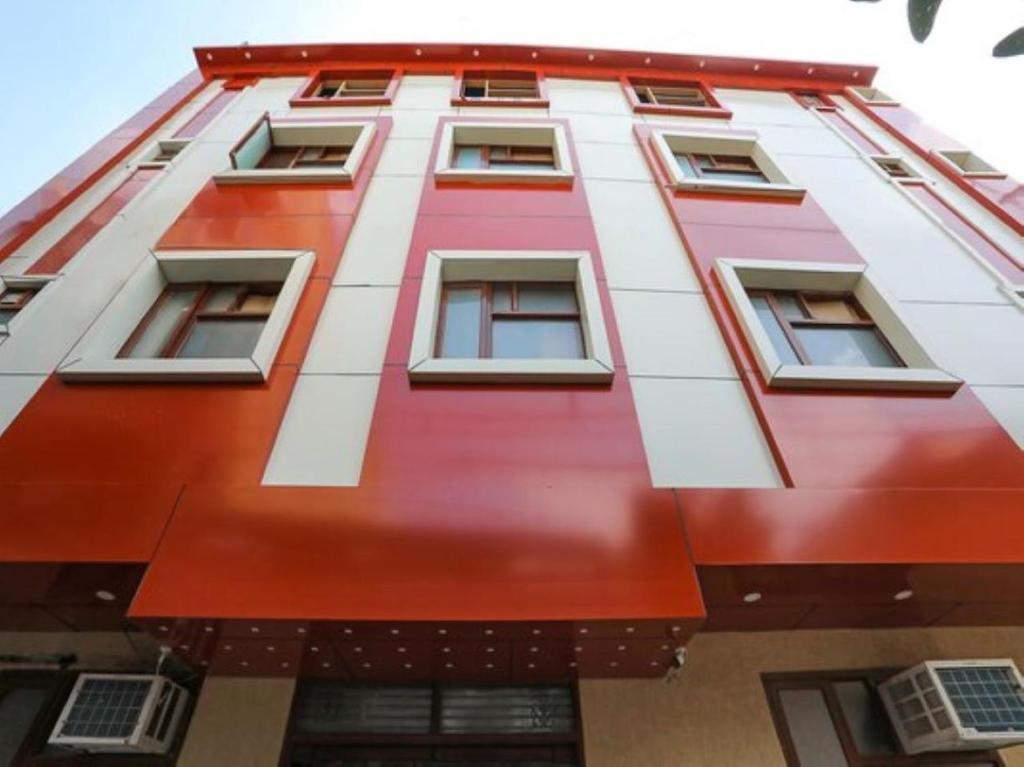 a tall red and white building with windows at HOTEL KRISHNA RESIDENCY in Amritsar