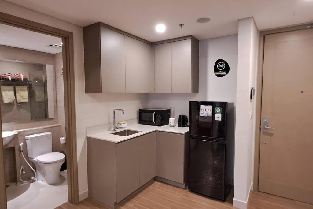 a small kitchen with a sink and a black refrigerator at gold coast pik BEACH ROOM 1br netflix wifi sofa bed in Jakarta