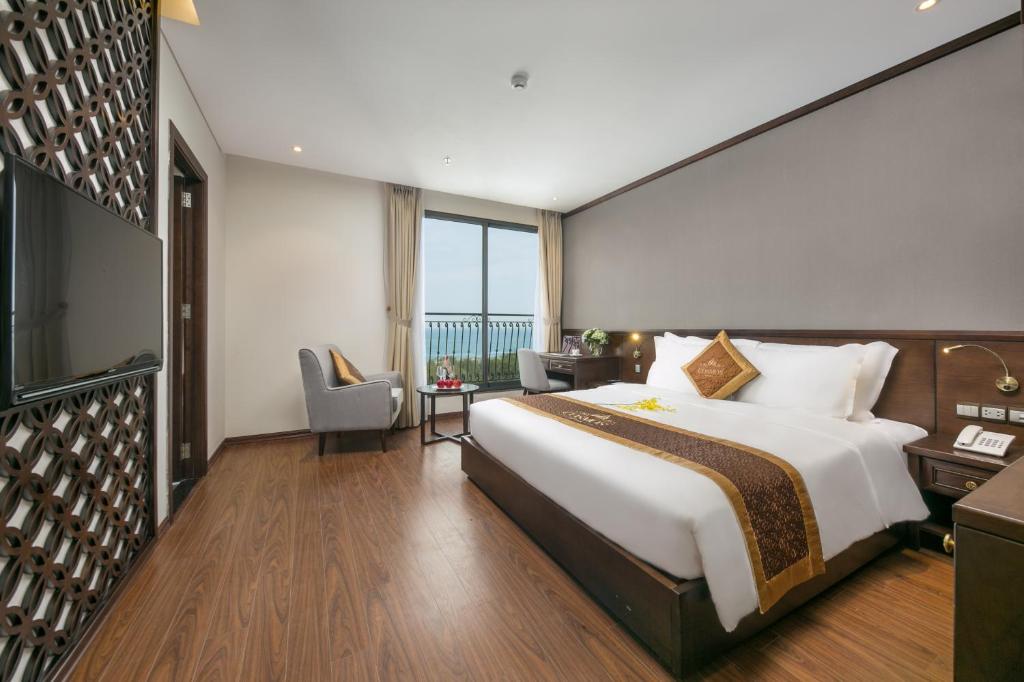 a hotel room with a large bed and a desk at Cosmos Hotel Danang in Da Nang