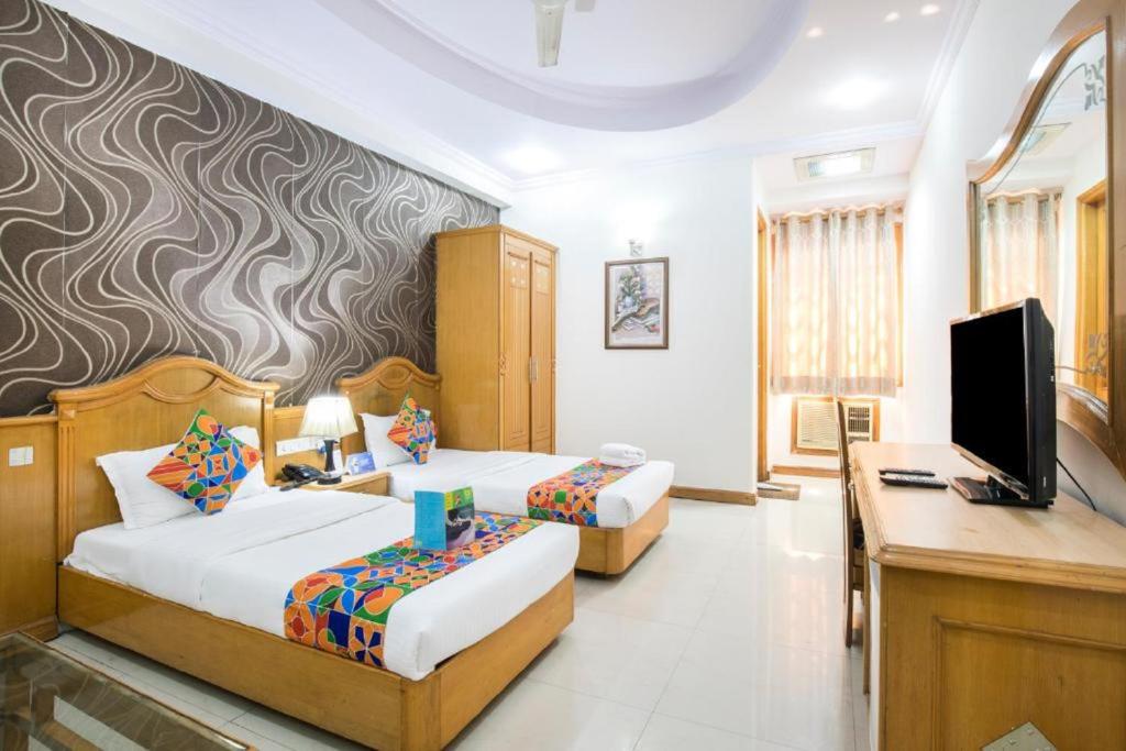 - une chambre avec 2 lits, un bureau et une télévision dans l'établissement Hotel Kochar Continental, à New Delhi