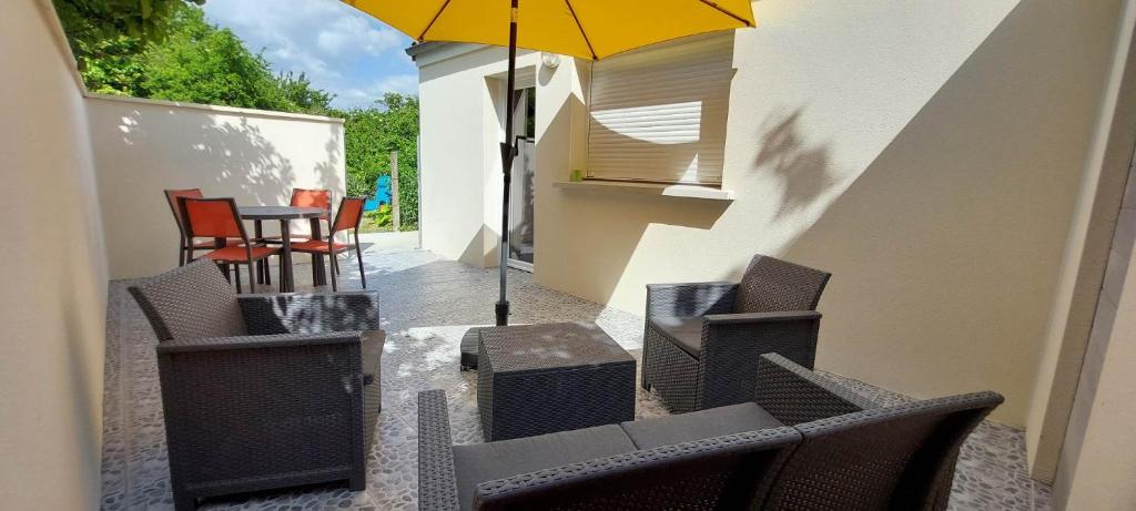 un patio avec des chaises et une table avec un parasol dans l'établissement Meublé de tourisme à l'entrée de Royan, à Médis