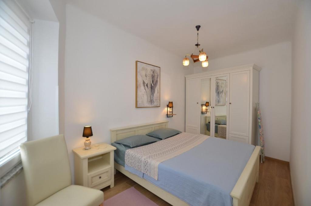 um quarto branco com uma cama e uma cadeira em Moris Apartman em Rovinj