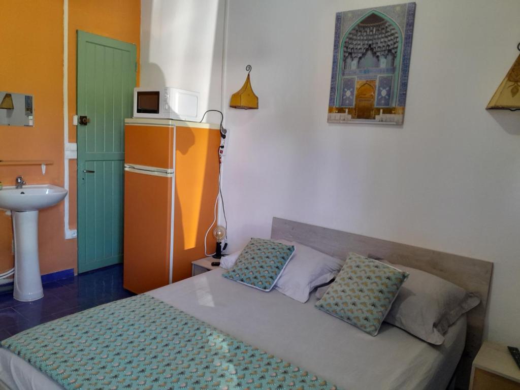 Schlafzimmer mit einem Bett und einer Mikrowelle an der Wand in der Unterkunft Le Tuléar - Aux 4 coins du monde in Saint-Pierre