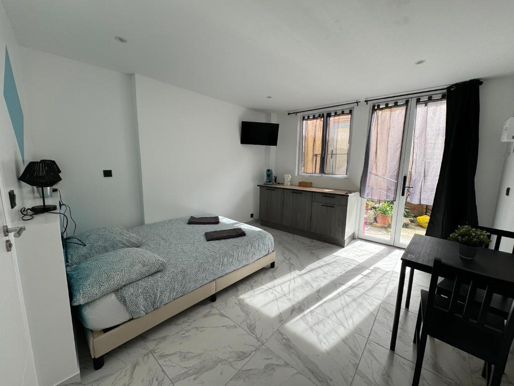 a white bedroom with a bed and a desk and window at La maison de Giulia Menton in Menton