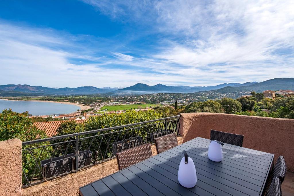 a table on a balcony with a view of a lake at Terra Di Sole - Vue mer et montagne in Grosseto-Prugna