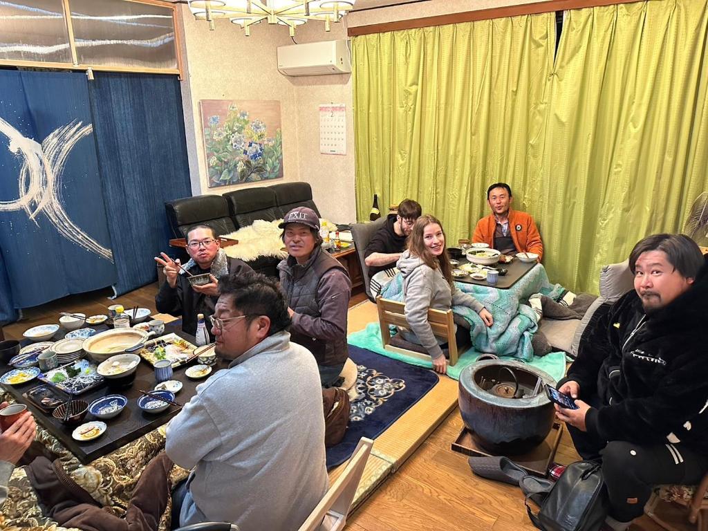 a group of people sitting around a table in a room at Guesthouse Oomiya base 大宮基地別荘 in Chiba