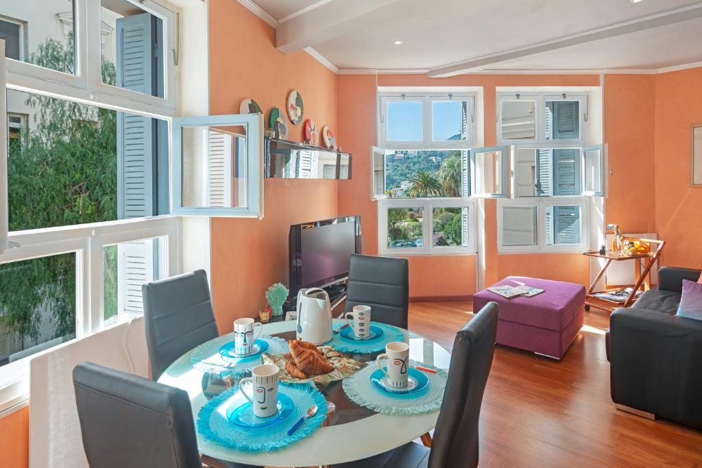 une salle à manger avec une table, des chaises et des fenêtres dans l'établissement Riviera Palace - Happy Rentals, à Menton