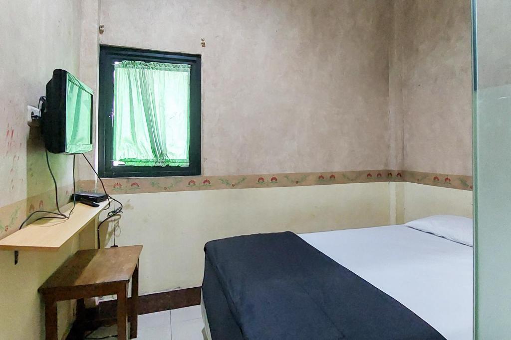 Dormitorio pequeño con cama y TV en Ni Hotel Syariah Bandara Soekarno Hatta Mitra RedDoorz en Selapajang