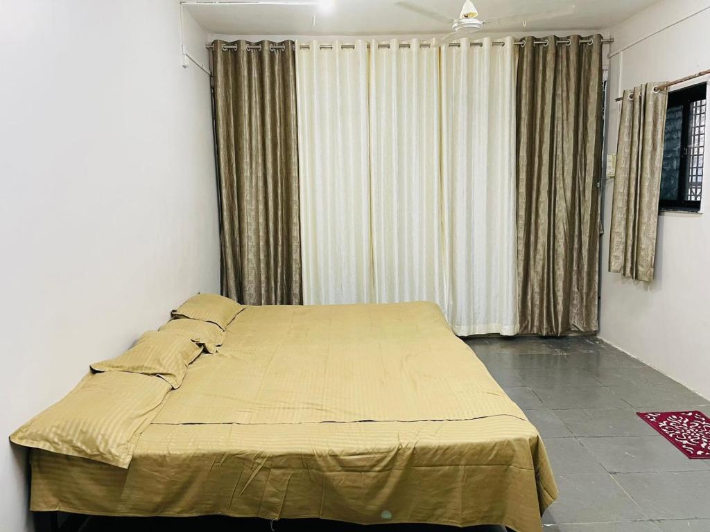 a bed in a room with a window with curtains at Tuljai Homestay in Tuljapur