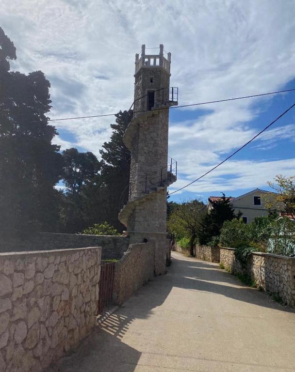 a stone building with a clock tower on a road at Apartments Silba in Silba