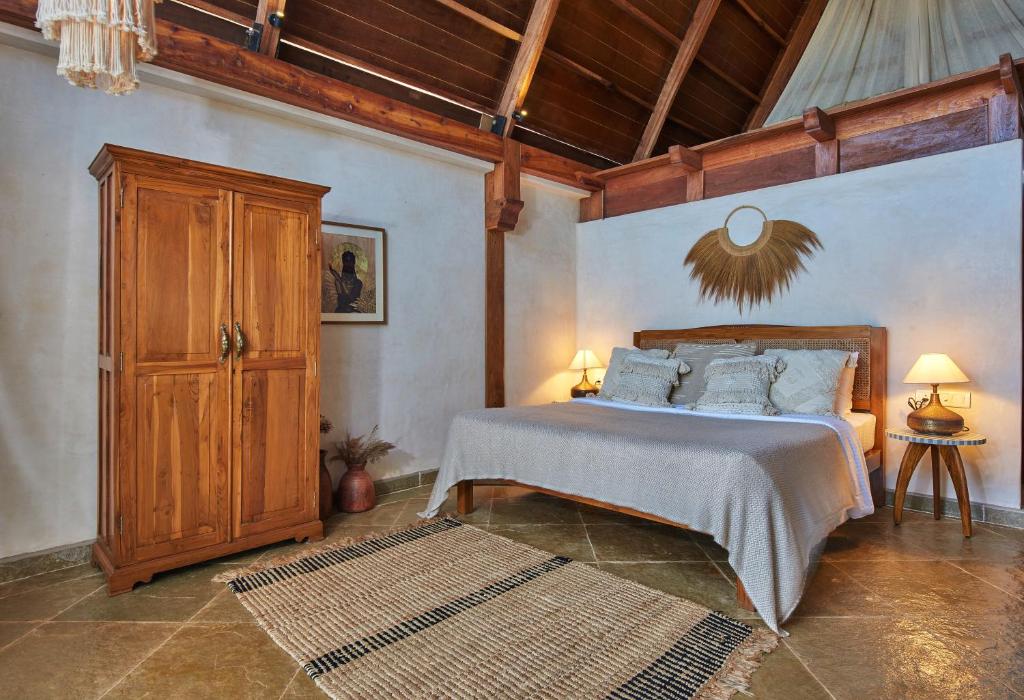 a bedroom with a bed and a wooden cabinet at Vaayu Kula mandrem in Mandrem