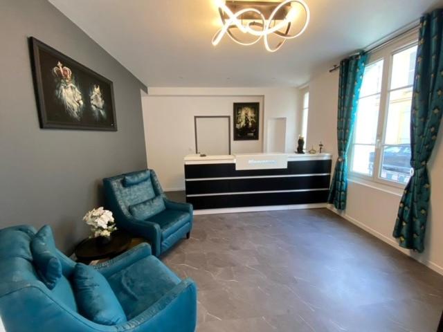 a living room with a blue couch and a sink at Hôtel Le Home Saint Louis in Versailles