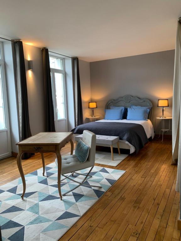a bedroom with a bed and a desk and a table at Hôtel SPA Le Miel des Muses in Brive-la-Gaillarde