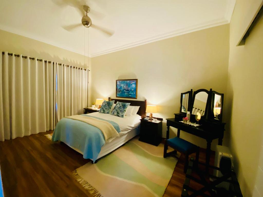 a bedroom with a bed and a table and a mirror at Rondeletia Cottage Guesthouse - premium self catering in Gillitts