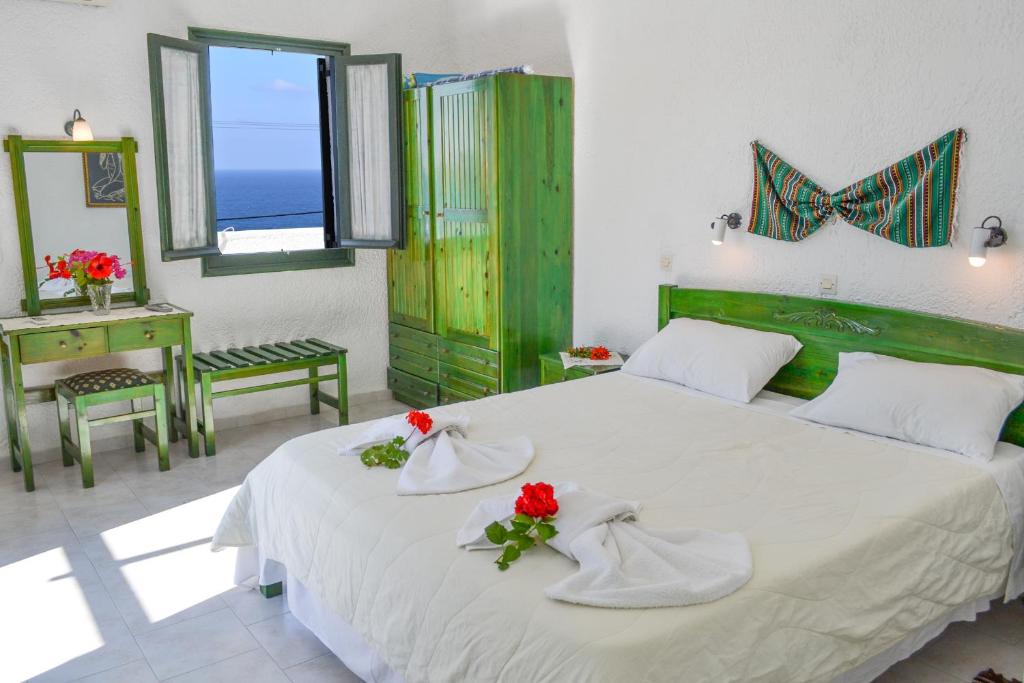 a bedroom with a white bed with red flowers on it at Hotel Finiki View in Foiníkion