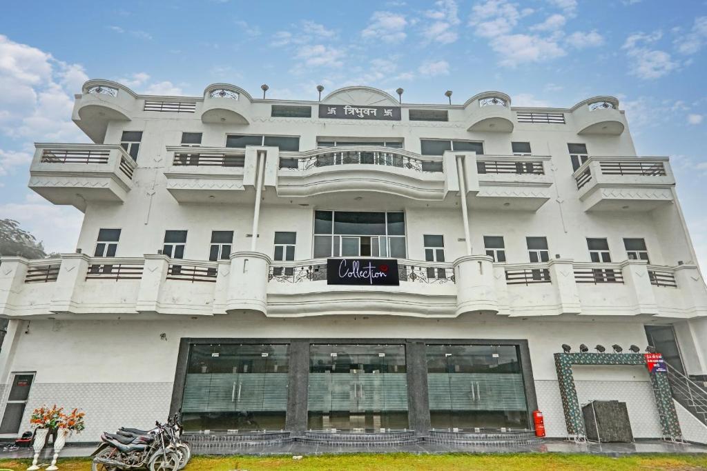 a large white building with a motorcycle parked in front of it at OYO Flagship Hotel Tri Palace in Kānpur