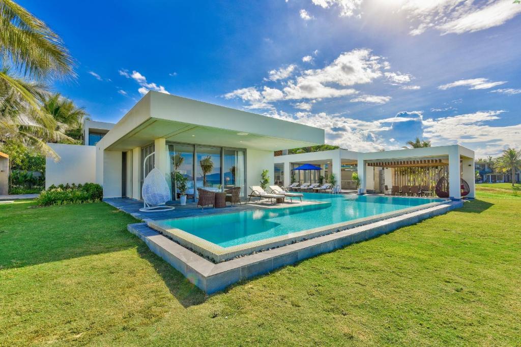 a villa with a swimming pool in front of a house at Ocean Luxury Villas Danang in Da Nang