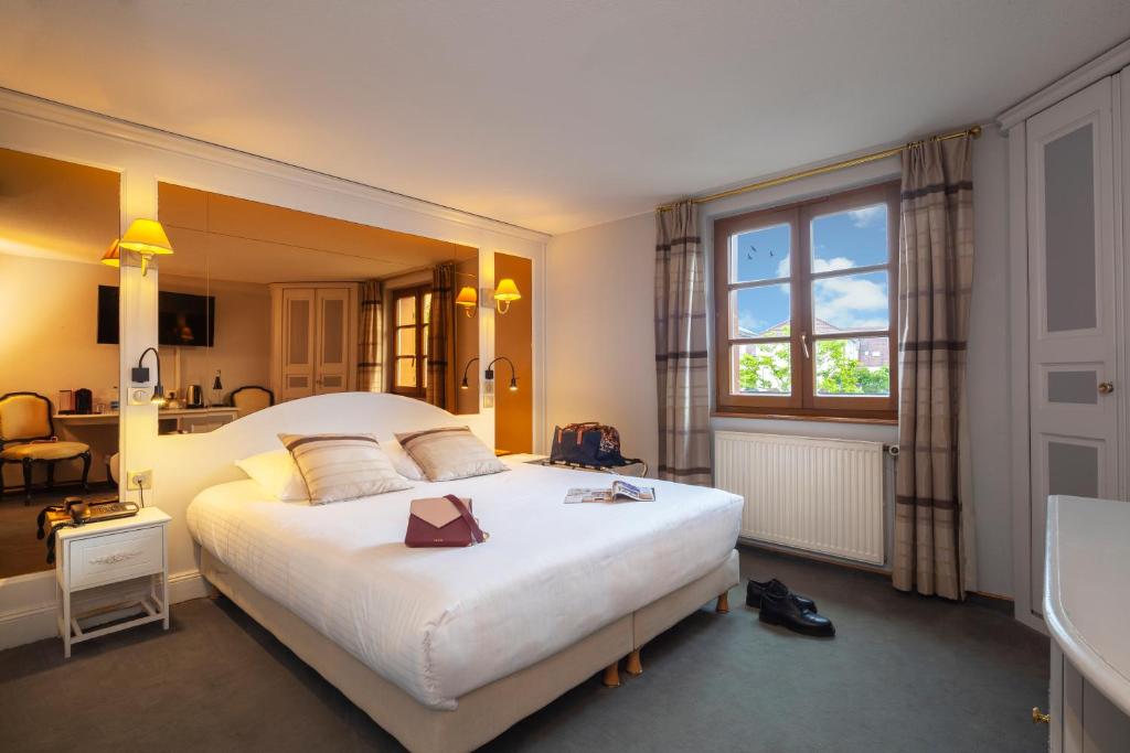 Un dormitorio con una gran cama blanca y una ventana en Hôtel Restaurant Relais De La Poste - Strasbourg Nord, en La Wantzenau