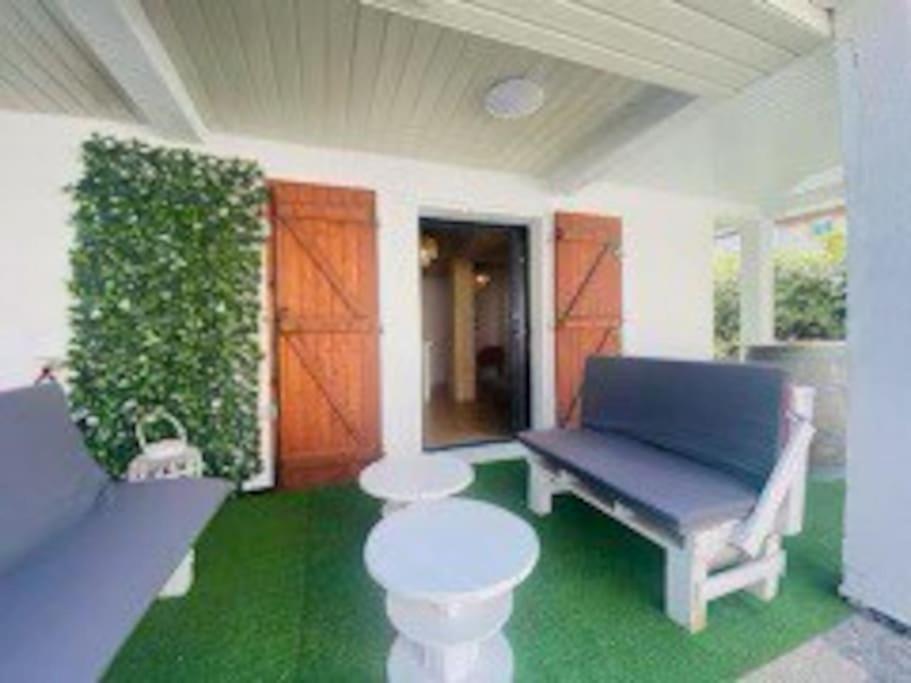 un porche avec un banc bleu et un sol vert dans l'établissement Joli T2 bas de chalet plage de Gruissan, à Gruissan