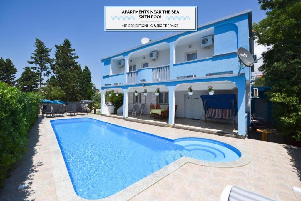 a villa with a swimming pool in front of a house at Pension Kolibri in Novalja