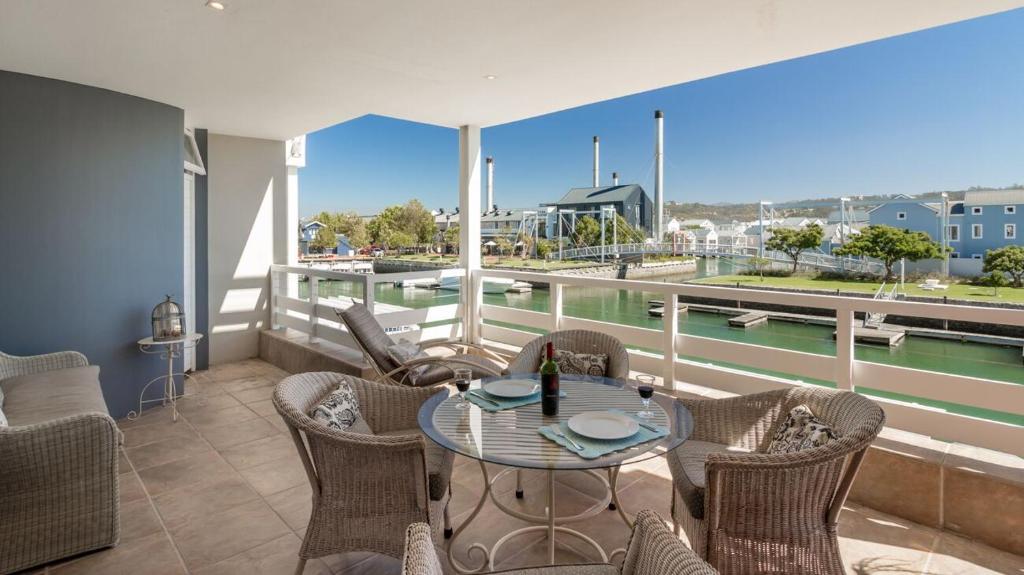 balcón con mesa y sillas y vistas al puerto en Sunny Dry Mill Apartment on Thesen Islands, en Knysna