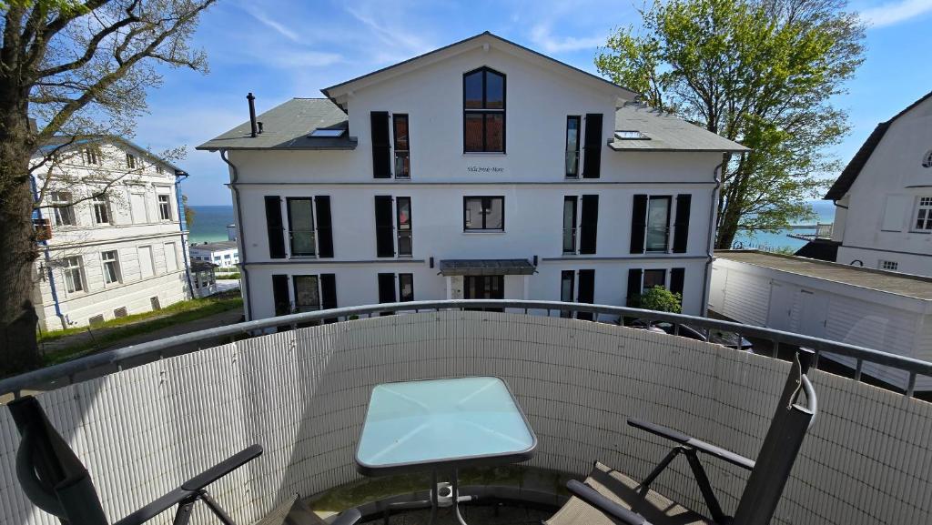 un banco blanco en un balcón con una casa blanca en Ferienwohnung Feuerstein, en Sassnitz