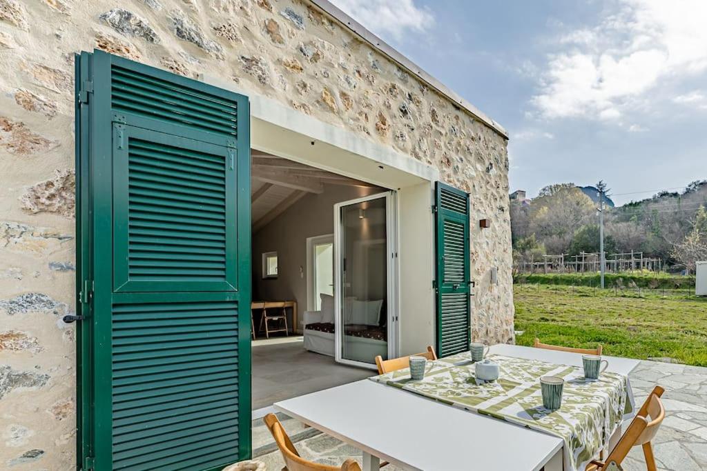 a stone house with green doors and a table and chairs at Charming one-floor villa with garden, car parking in Albisola Superiore