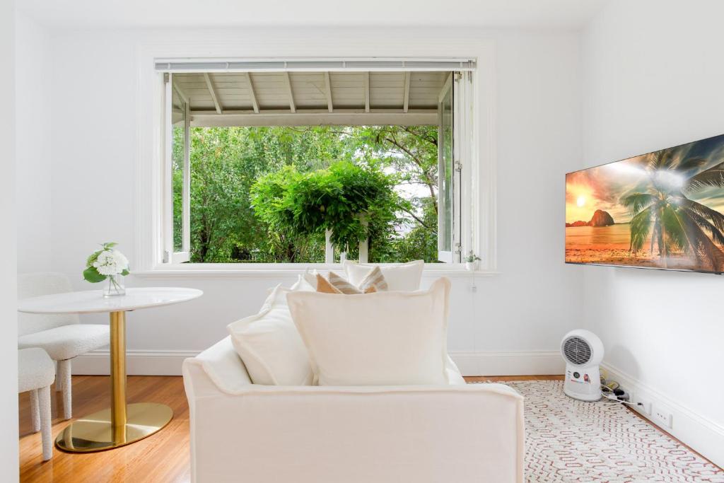 een witte woonkamer met een witte bank en een raam bij Cosy Inner West Studio with Courtyard in Sydney