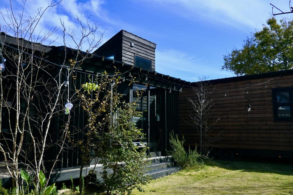 una casa di mattoni con un albero di fronte di Tiny Base The River HOUSE & TRAILER a Kawazu