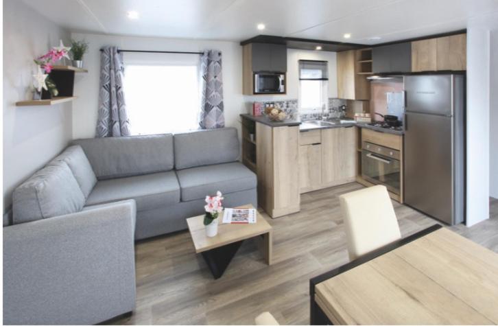 un salon avec un canapé et une cuisine dans l'établissement Mobilhomme camping, à Fréjus