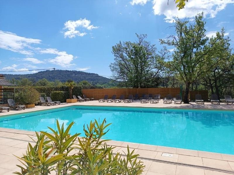 une grande piscine bleue avec des chaises et des arbres dans l'établissement Camping maeva Escapades Le Domaine des Chênes Blancs, à Croagnes
