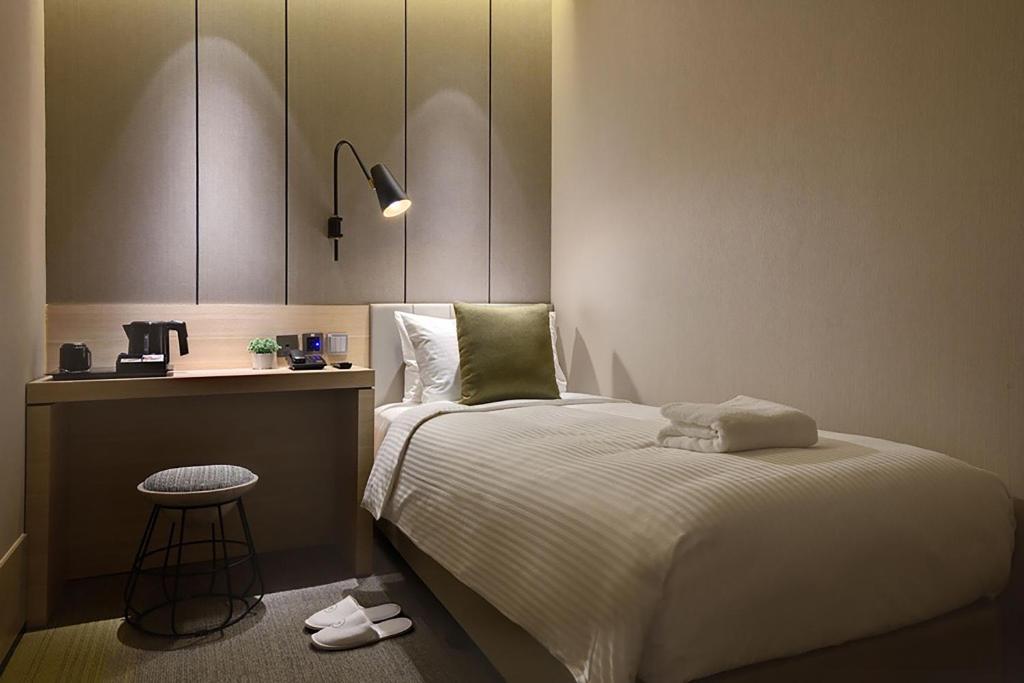 Aerotel Transit Hotel, Terminal 1 Airside في سنغافورة: غرفة نوم بسرير وطاولة ومقعد