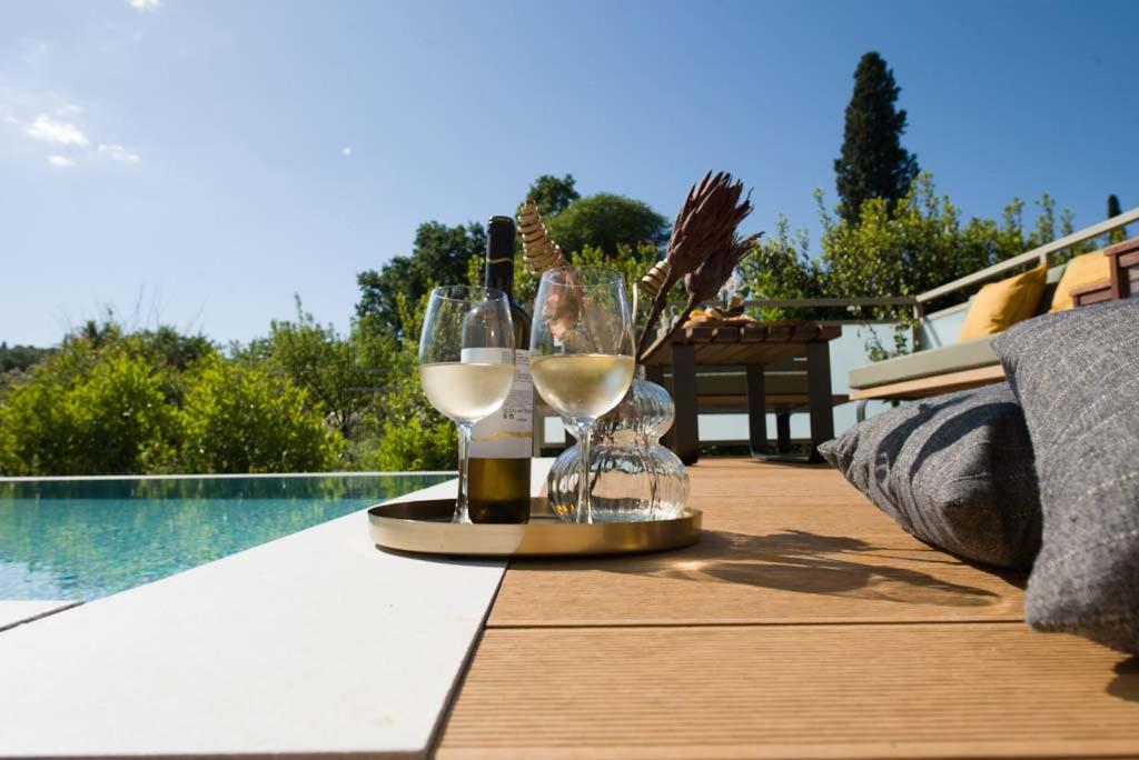 een dienblad met wijnglazen op een tafel naast een zwembad bij Spiretos in Potamós