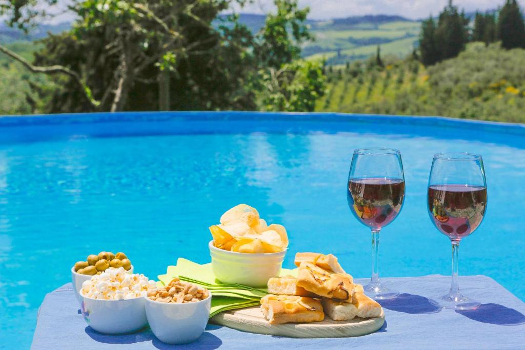 einen Tisch mit zwei Gläsern Wein und einem Teller Essen in der Unterkunft Fattoria la Luna 15 min da Firenze trilocale Archetti piscina e wi-fi in Lastra a Signa