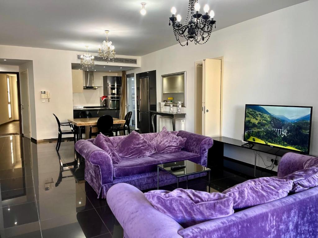 a living room with purple couches and a kitchen at Apartment near Aretaeio Hospital Platform 357 in Nicosia