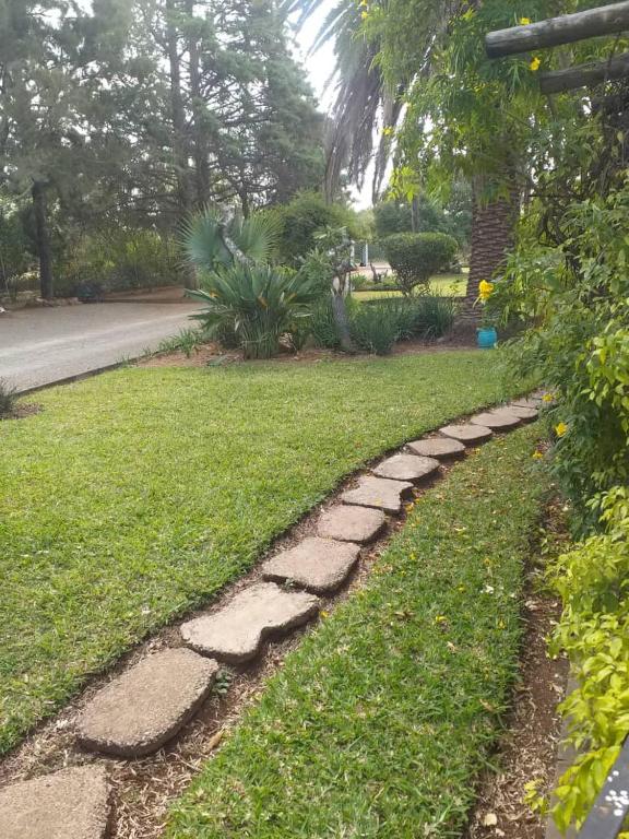 a garden with a stone path in the grass at Beautiful No Fuss Serene 4-Bed House in Bulawayo in Bulawayo