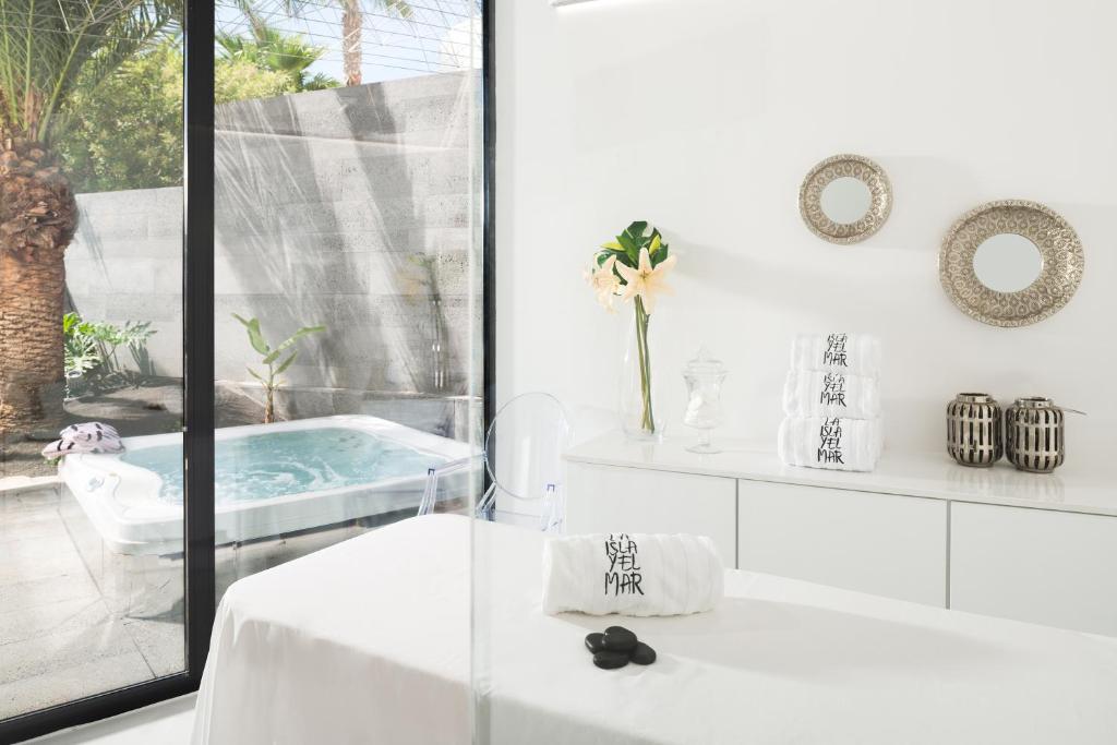 a white bathroom with a tub with a table and a window at La Isla y el Mar, Hotel Boutique in Puerto del Carmen