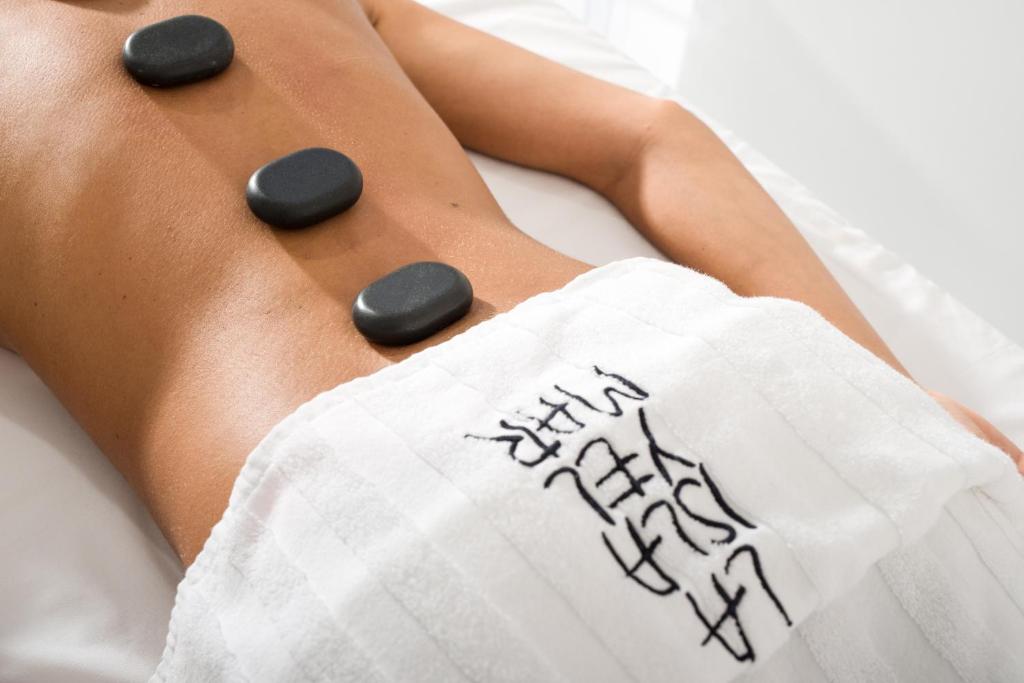 a woman laying on a bed with black pills on her buttocks at La Isla y el Mar, Hotel Boutique in Puerto del Carmen